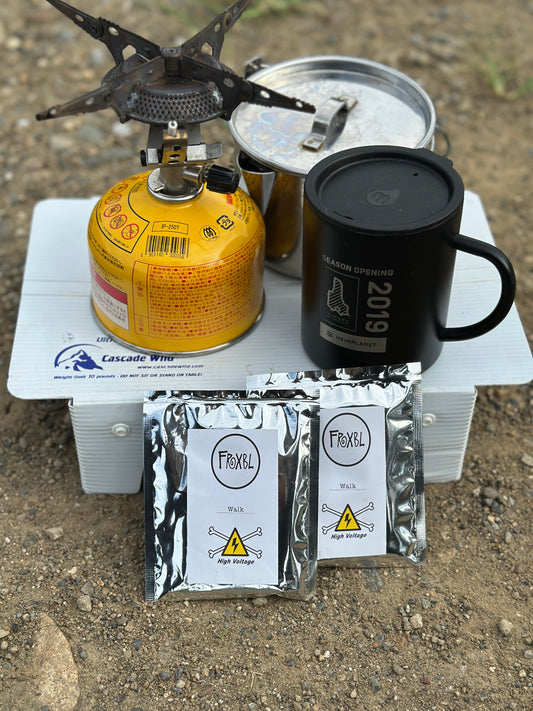 アウトドア用バーナーとマグカップの前に置いたFRXBL COFFEE Walk blend ドリップバッグ2袋